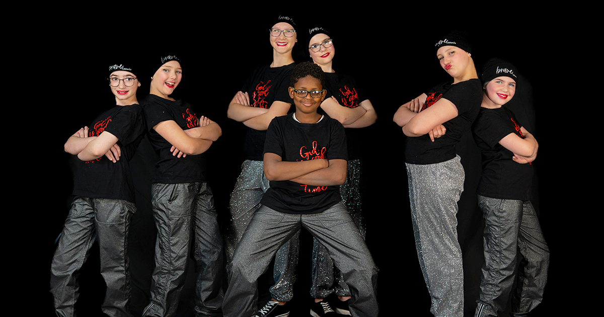 A group of smiling dancers in an arms-crossed pose